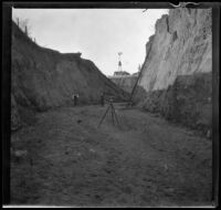 Surveyors standing in a ditch formed by a washout of the Southern Pacific Railroad, San Dimas vicinity, about 1899