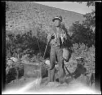 H. H. West Jr. holding fish and fishing gear, Inyo County vicinity, about 1930