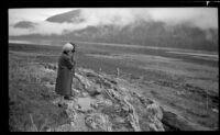 Mertie West and an unknown person stand on the shore during low tide, Sitka, 1946