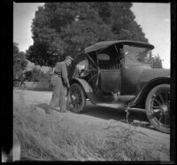 Al Schmitz working to fix a flat tire on a car, Mendocino County vicinity, 1915