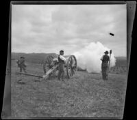 Two servicemen fire a cannon in Los Angeles National Cemetery during Decoration Day while a spectator watches, Los Angeles, about 1895