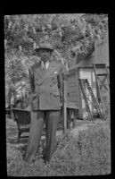 H. H. West stands in front of a wisteria plant in his backyard, Los Angeles, 1942