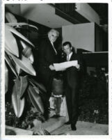 Richard J. Neutra and son, Dion outside house looking at plans [view 1]