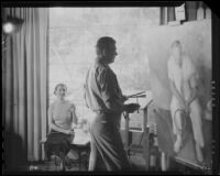 Stanley Reckless painting in the studio of his Silver Lake home as his wife (?) observes, Los Angeles, 1930-1939