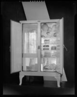 Open icebox with a block of ice and food inside, 1930-1937