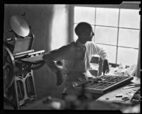 Walter Willard "Spud" Johnson seated next to his hand press, Santa Fe or Taos, 1932