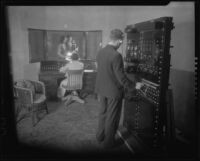 Man and woman speaking at a sound stage or radio station with technicians at the controls, 1930-1950