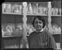 Mina Conselman standing next to her milk glass collection in her home, Eagle Rock, 1930-1939
