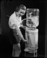 Photograph of a tennis player getting a glass of water from an Arrowhead water dispenser, Los Angeles, between 1935