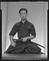 Seated Japanese man with sword, 1930-1960