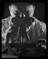 Man looking through a microscope, 1930-1960