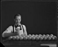 Grocer holding a glass of orange juice behind a table full of oranges for Sunkist advertisement, 1937