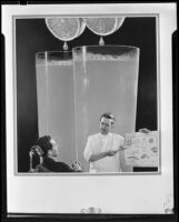 Photomontage image with a dentist showing a patient a chart with large glasses of orange juice behind them, 1935