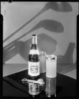 Bottle of "Mission Dry Sparkling" beverage on a table beside 2 full glasses, Los Angeles, circa 1930