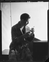 Man in a bathrobe looking at a toothbrush for a "Sunkist dental" advertisement, 1935