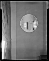 View of a round mirror reflecting 4 framed fashion illustrations on a wall in "Irene LTD," a dress shop of designer Irene Lentz Gibbons, Los Angeles, (circa 1930?)