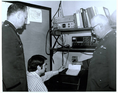 Three men check emergency equipment