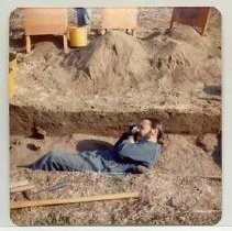 Photographs of landscape of Bolinas Bay. Archeaologist laying in a trench taking a photograph