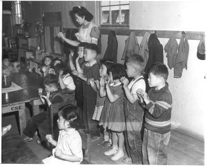 "Japanese Tots Sing English Songs--A kindergarten tots under supervision of Aiko Sumoge, assistant teacher, sing an English folk song in class at the Tule Lake, California, Japanese relocation center."--caption on photograph