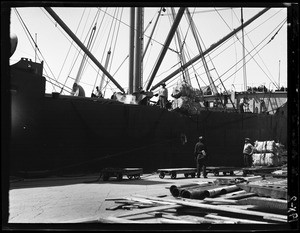 Dockworkers loading a large ship in Los Angeles Harbor