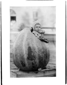 Little girl standing inside large pumpkin