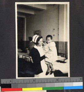 A Western nurse holding a Chinese boy, Shanghai, China, ca. 1939