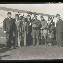 Group of people standing next to a bi-wing airplane