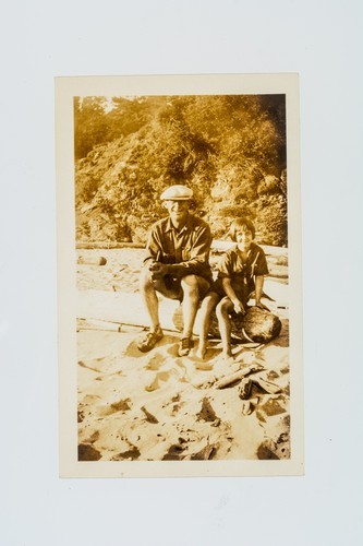 Colby E. "Babe" Slater sitting on log with unidentified girl on a North Coast Beach