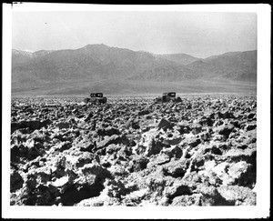 Two cars driving on a road through the salt beds in the Devil's Golf Course, Death Valley, ca.1900-1950