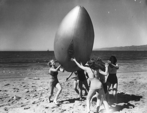 Women at the beach with giant "football", view 1