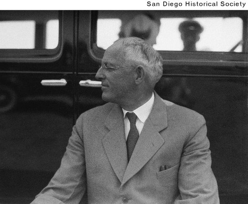 Edward Fletcher seated beside an automobile