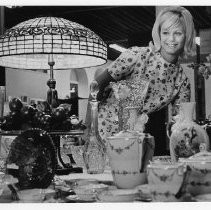 View of Shelley Kloepfer, the Maid of Contra Costa County and runnerup in the Maid of California admires some antique glass and dinner ware in the Woman's Building at the California State Fair. This was the last fair held at the old fair grounds