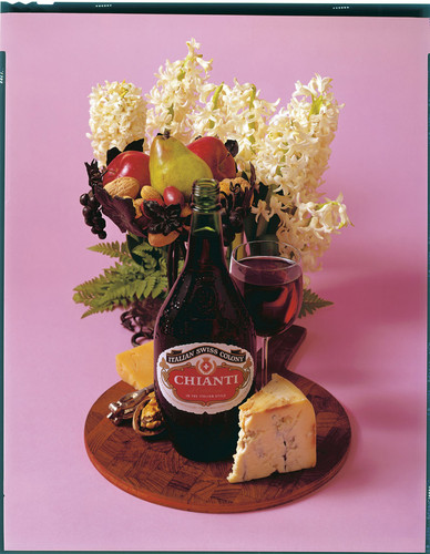 A bottle of Italian Swiss Colony Chianti with cheese, walnuts and a bouquet of flowers