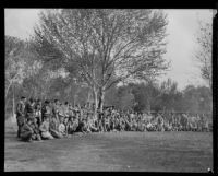 Boy Scouts grouped in a half circle at a camping event in a park, circa 1935