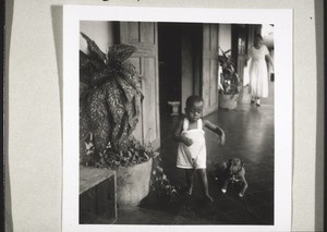 African child with dog in front of the mission station