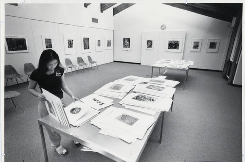 Woman looks through paintings, Scripps College