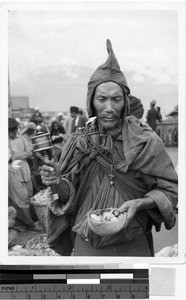Tibetan man with a prayer wheel and bowl, Tibet, ca. 1920-1940