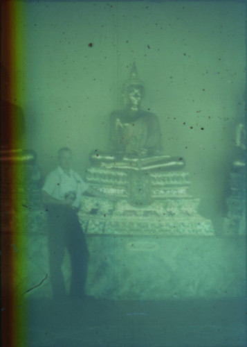 Unidentified man standing next to golden Buddha statue