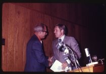 Two men shaking hands at podium