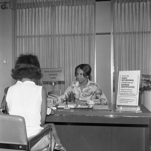 Broadway Federal Savings and Loan employee helping a customer, Los Angeles, 1974