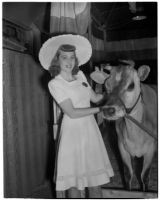 Donna Larson and Elsie the Borden Cow, star of the 1940 film "Little Men," Los Angeles, 1940