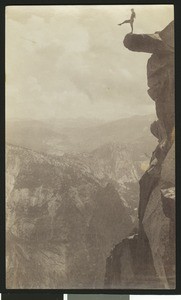 Man posing on one leg on an overhanging rock at Glacier Point in Yosemite National Park, ca.1920-1930
