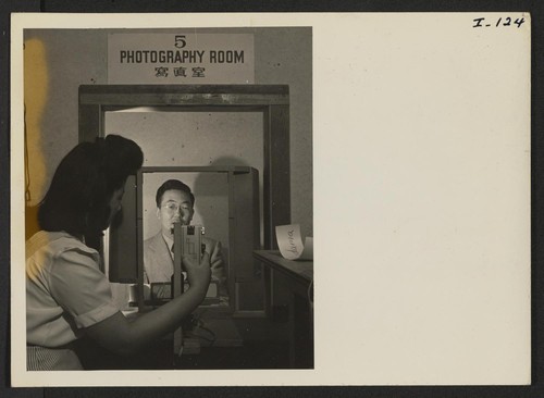 Photographer Yuki Shirakawa, of the Relocation Department, is taking a picture of Mr. Tom Oki for the file and identification