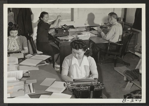 A view of the Reports Office, at this War Relocation Authority Center. Russell Bankson, Reports Officer, is shown on the far right. Photographer: Stewart, Francis Topaz, Utah