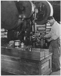 Hydraulic press operator laminating sections of flooring or counter tiles, 1950s or 1960s