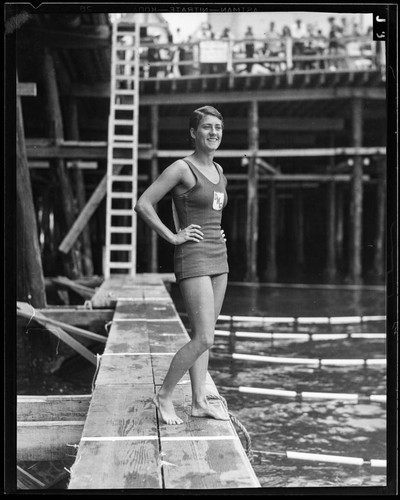Woman swimmer posing next to lanes of swimming competition, Santa Monica