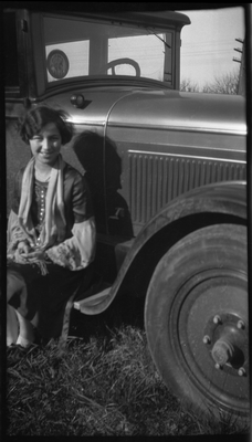 Young woman sitting on running board of automobile