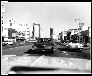 View of Wilshire Boulevard from a car showing the May Company building, April 28, 1964
