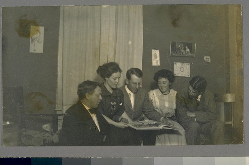 [Unidentified persons looking at book.]