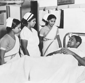 Missionshospitalet i Tirukoilur, Arcot, Sydindien. Indiske sygeplejersker ved en landsmands sygeseng. (Anvendt i: Dansk Missionsblad nr 19/1953, forsiden)